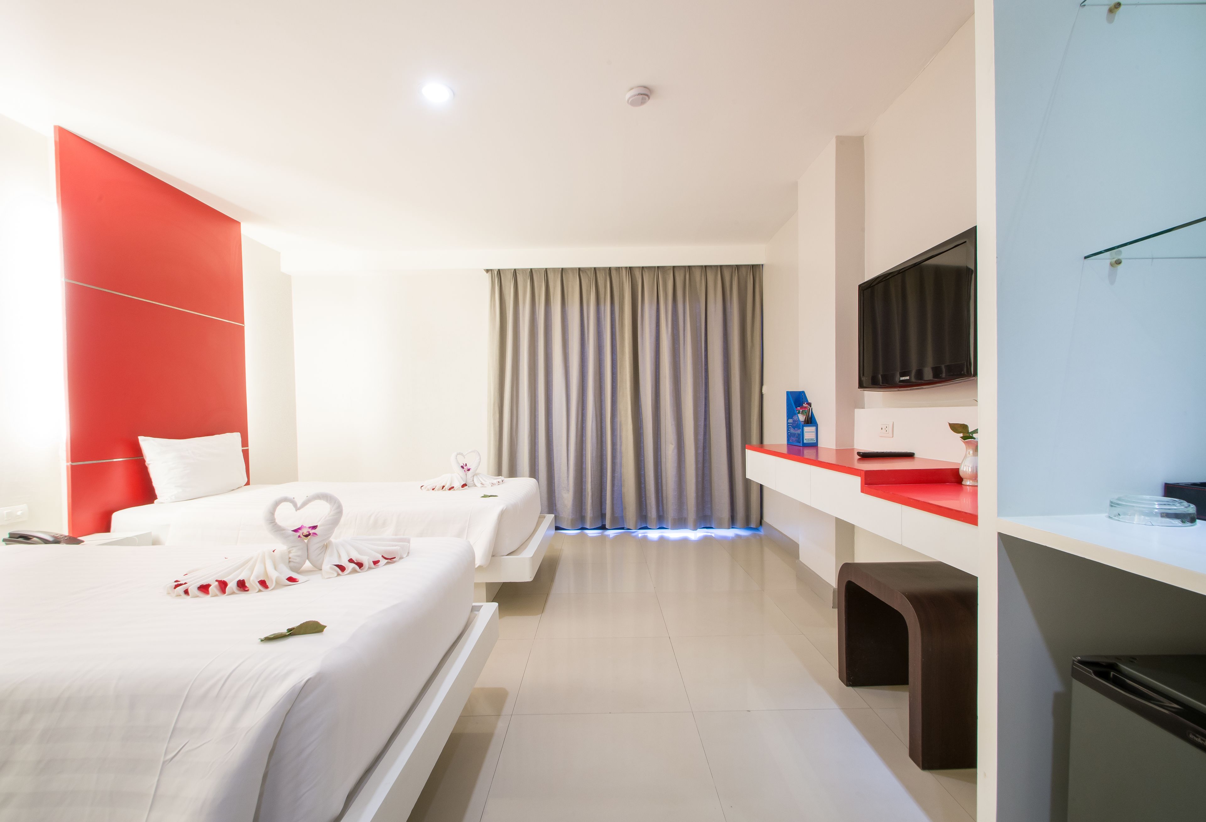 A hotel room with a bed, a desk, a television, and a bathroom.