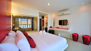 A modern hotel room with a large bed, a TV, a mirror, and a red accent wall. - Alfresco Phuket Hotel (Patong)