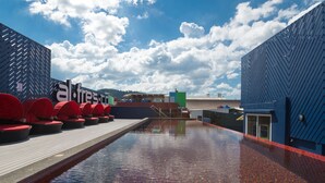 A rooftop pool area with red lounge chairs and a clear view of the sky. - Alfresco Phuket Hotel (Patong)