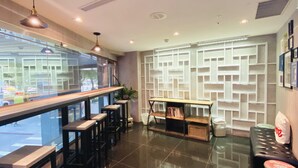 A modern bar area with a long counter, stools, and a decorative wall with shelves. - Burgary Hotel (Taipei)