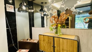 A reception area with a wooden cabinet, a black leather bench, a world map on the wall, and a 'No Smoking' sign. - Burgary Hotel (Taipei)