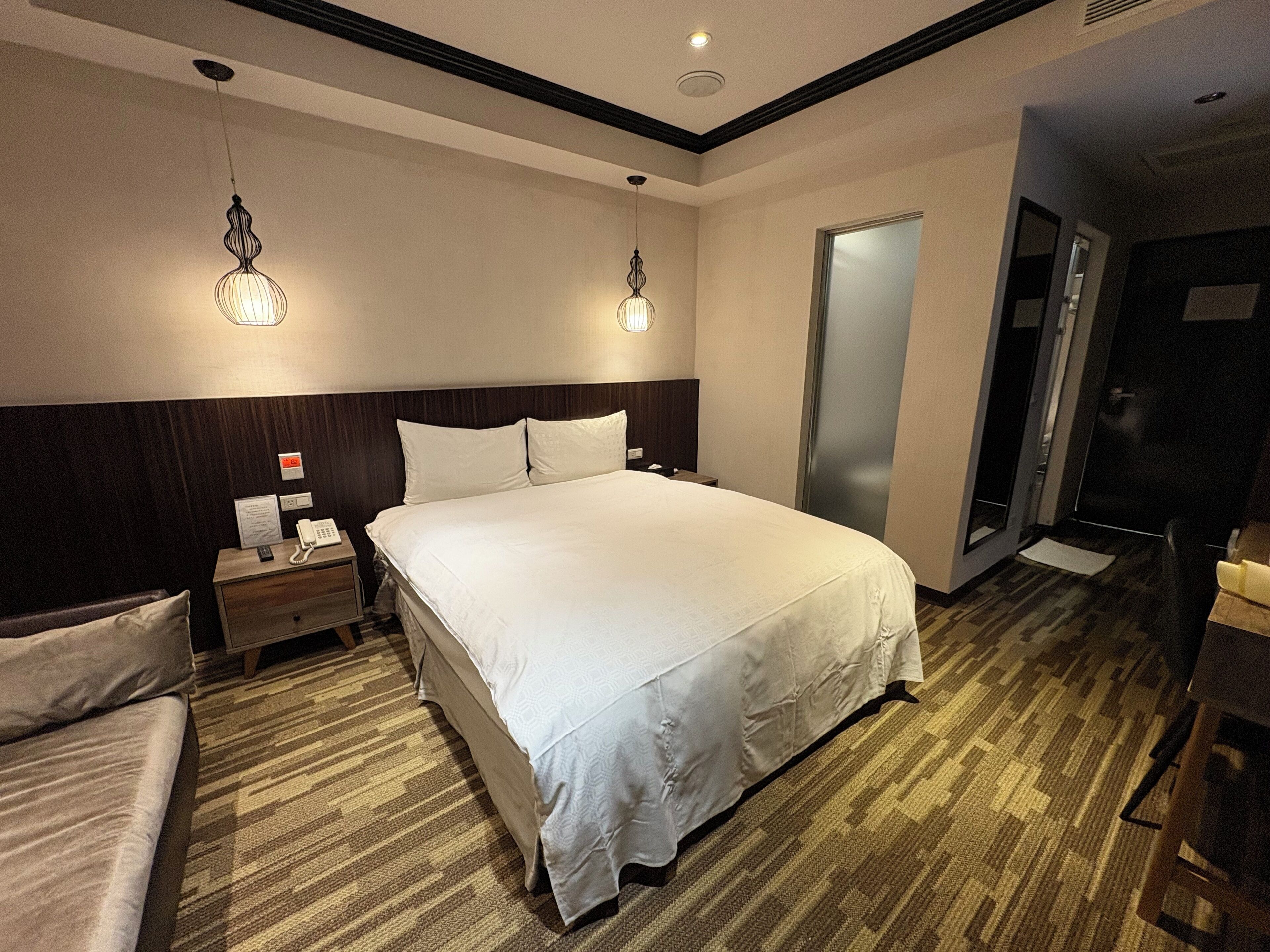 Une chambre d’hôtel avec un grand lit, deux tables de chevet, une commode, un bureau et une chaise.
