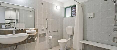 Un bany modern amb un lavabo, vàter, dutxa i baranes.