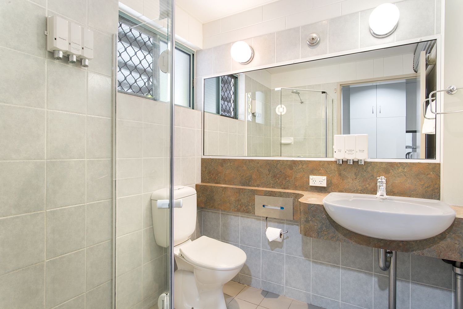 Une salle de bain moderne équipée de toilettes, d’un lavabo et d’une douche à parois de verre.