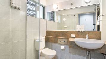 Une salle de bain moderne équipée de toilettes, d’un lavabo et d’une douche à parois de verre.