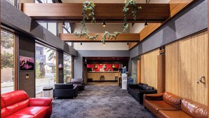 A lobby with a reception desk, two leather sofas, a coffee table, and a carpeted floor. - Select Inn Fujisan Gotemba (Gotemba)