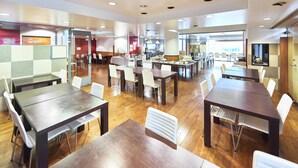A spacious dining area with multiple tables and chairs, a reception desk, and a view of the city through large windows. - Select Inn Fujisan Gotemba (Gotemba)