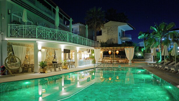 Una piscina con zona de bar, mobiliario de exterior y una terraza cubierta.