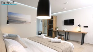 Un dormitorio moderno con una cama grande, un escritorio, un televisor y una zona de ducha.