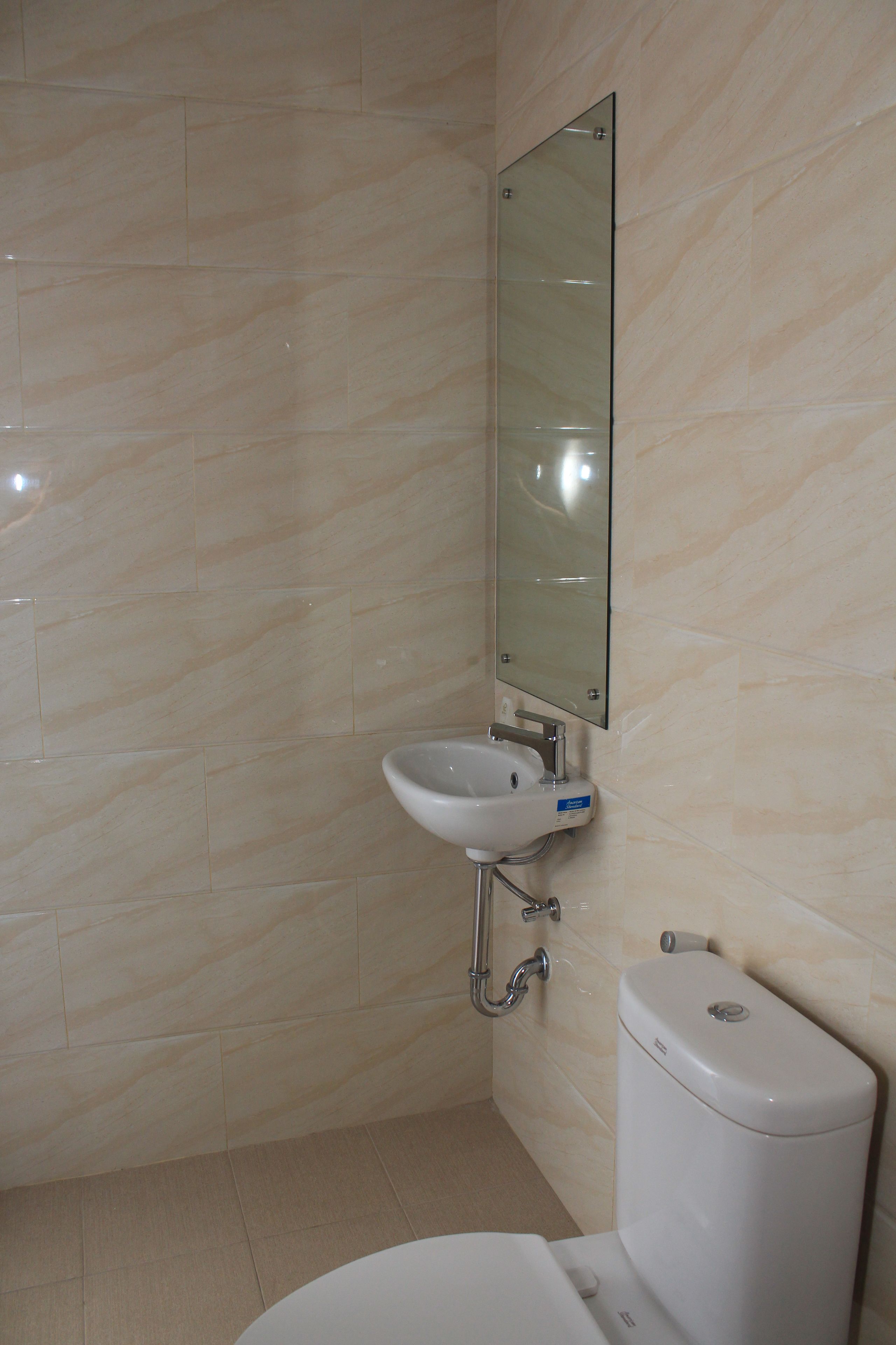 Un baño con lavamanos blanco, espejo e inodoro.