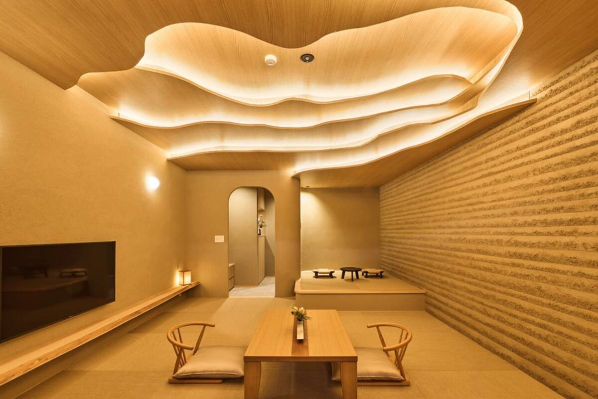 A modern interior with a wooden ceiling, a dining area with a table and chairs, and a seating area with benches.
