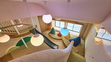 A modern interior with a spiral staircase, a slide, and a cozy seating area with cushions.