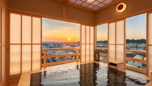 Un onsen japonés tradicional con vistas a la puesta de sol sobre un paisaje urbano.