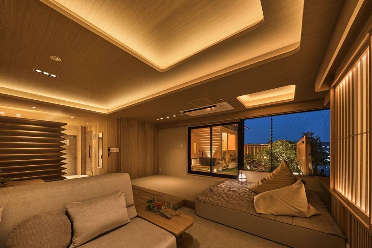 A modern interior with a sofa, a small table, and a view of the outdoors at night.