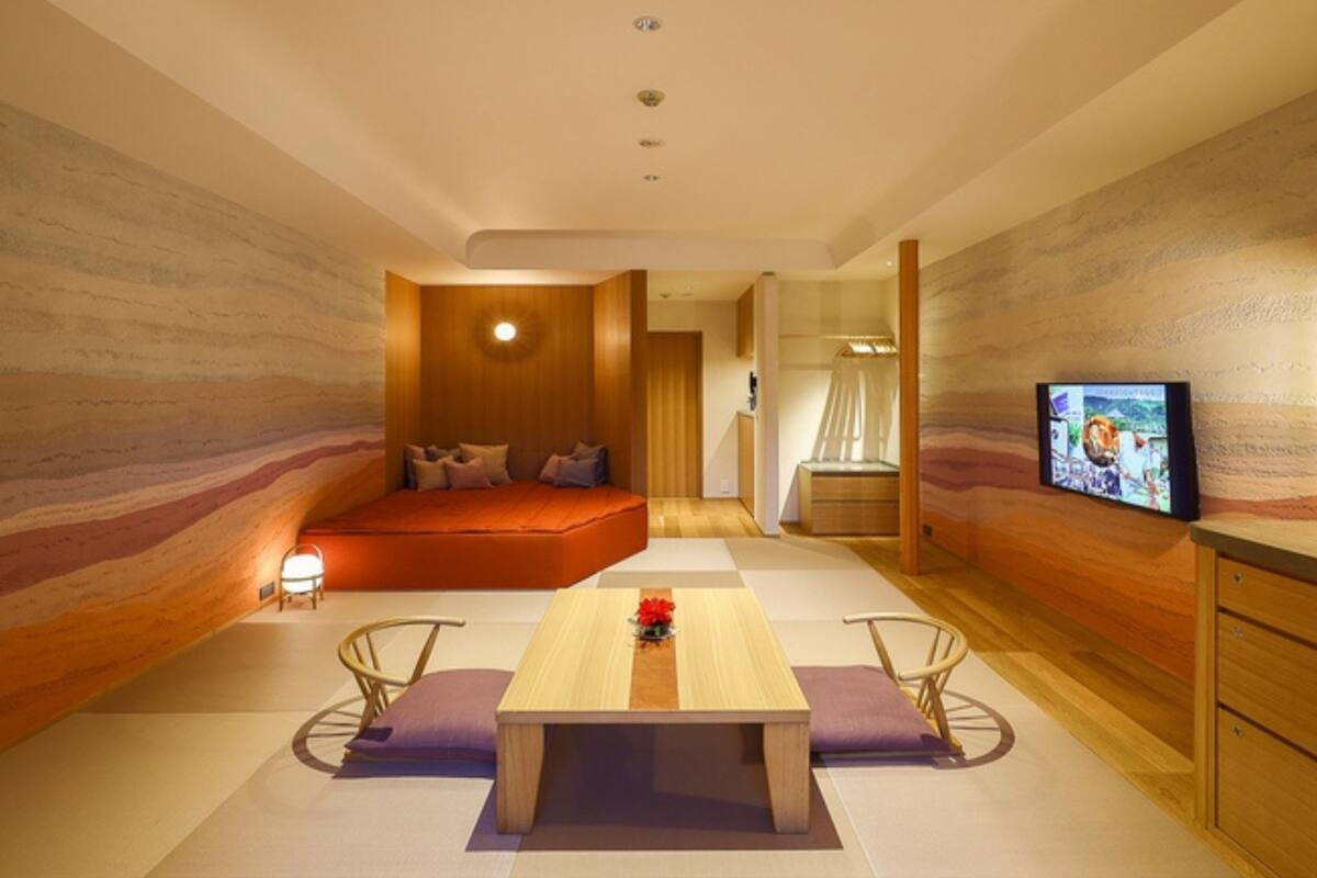 A modern room with a wooden floor, a central table, a sofa, and a TV on the wall.