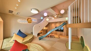 A modern interior with a staircase, cushioned seating areas, and a wooden floor.