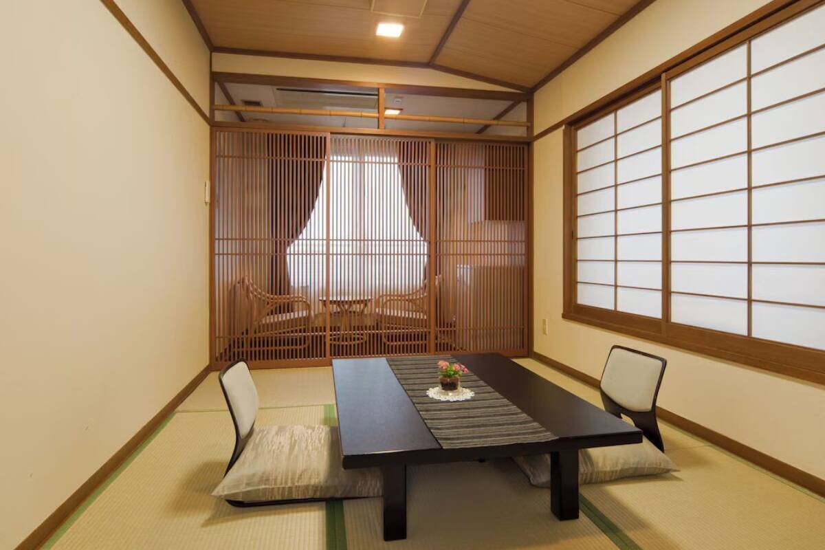 A traditional Japanese room with tatami flooring, a low table, and sliding doors.