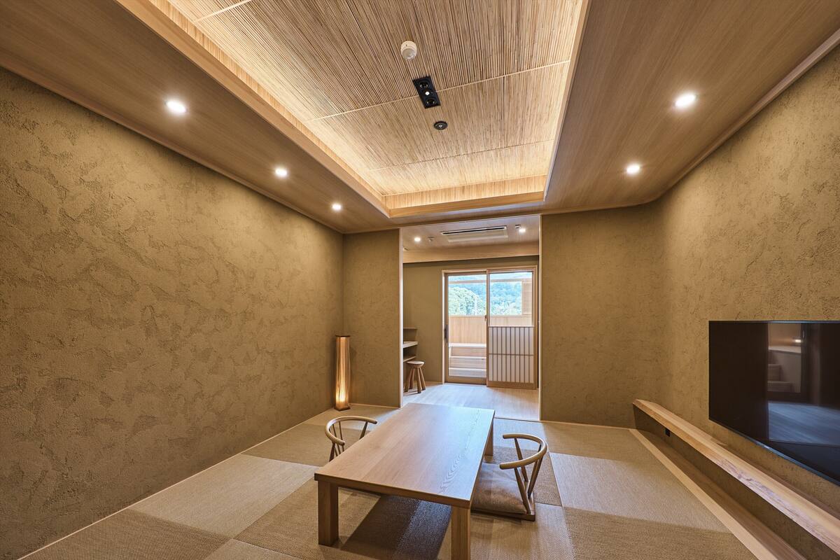 A modern room with a wooden ceiling, a large table, and a TV on the right.