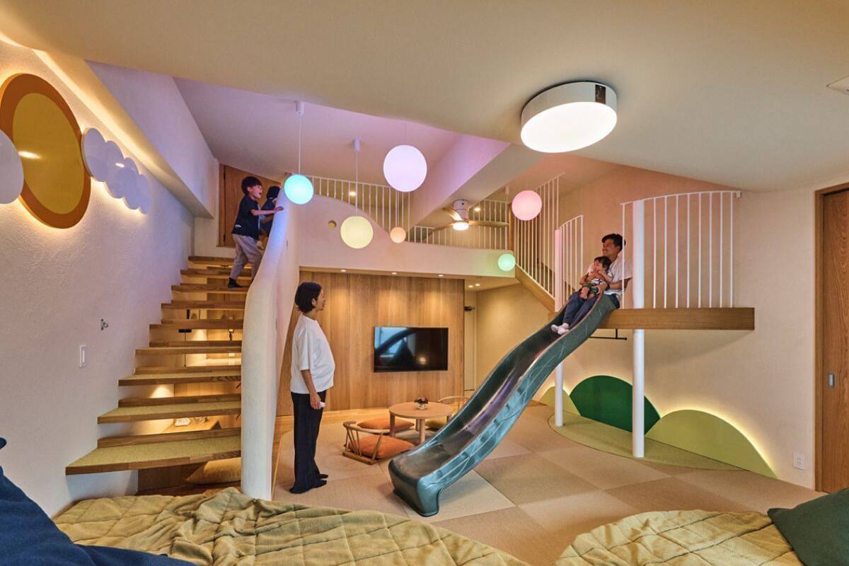 A modern interior with a wooden staircase, a children's slide, and a flat-screen TV in a cozy living area.