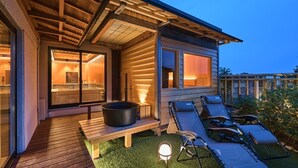 Una casa moderna con terraza de madera, jacuzzi y mobiliario exterior.