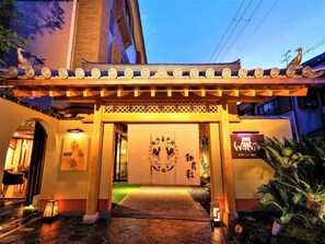 A traditional Japanese building entrance with a decorative gate, a signboard, and a well-lit pathway leading to the entrance. - Hotel New Wakasa (Nara)