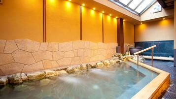 A hot spring area with a stone wall and a wooden deck.