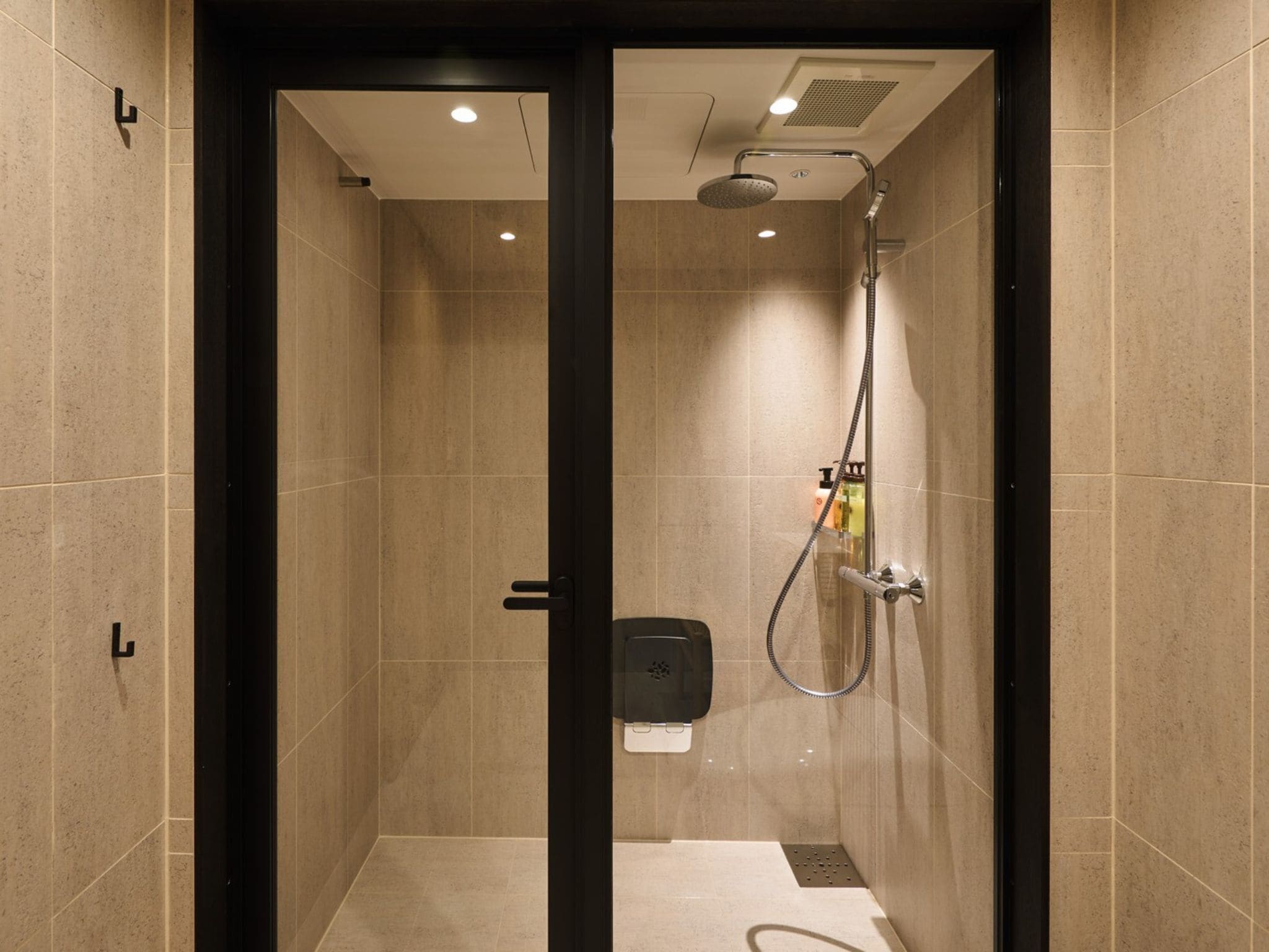 A modern shower area with a glass door, a handheld showerhead, and a control panel.
