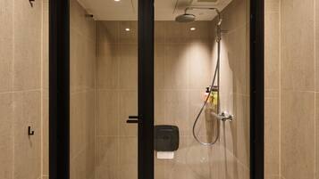 A modern shower area with a glass door, a handheld showerhead, and a control panel.