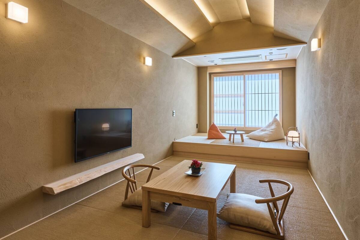 A modern living room with a flat-screen TV, a wooden table, and a sofa with cushions.