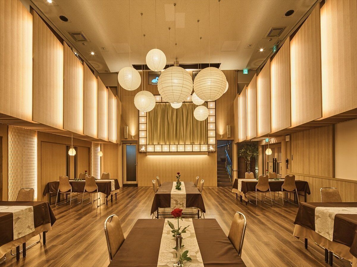 A spacious dining area with high wooden walls, multiple tables, and hanging spherical light fixtures.