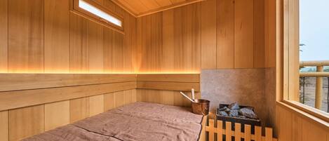 A wooden sauna room with a bench, a small heater, and a window.