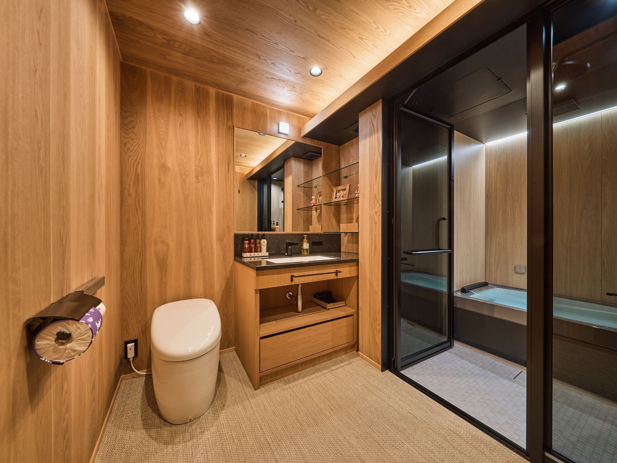 A modern bathroom with wooden walls, a glass shower enclosure, and a built-in sink.
