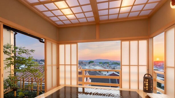 Un onsen japonés tradicional con vistas a la ciudad al atardecer.