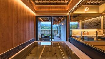 Un bagno moderno con pavimento in legno, cabina doccia in vetro e vista su un paesaggio montuoso.