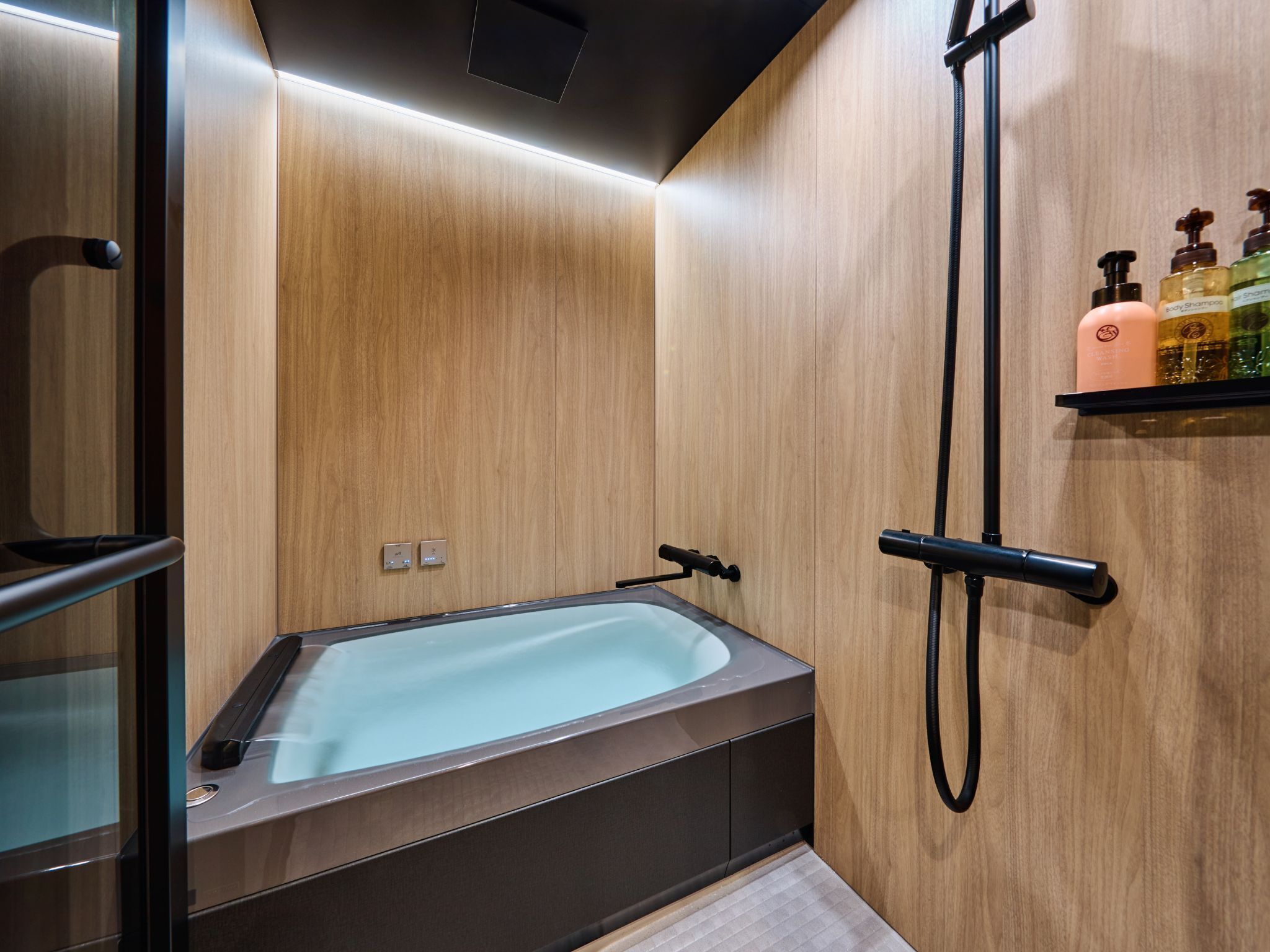 Une salle de bain moderne avec une baignoire intégrée, une douche et une étagère pour les articles de toilette.