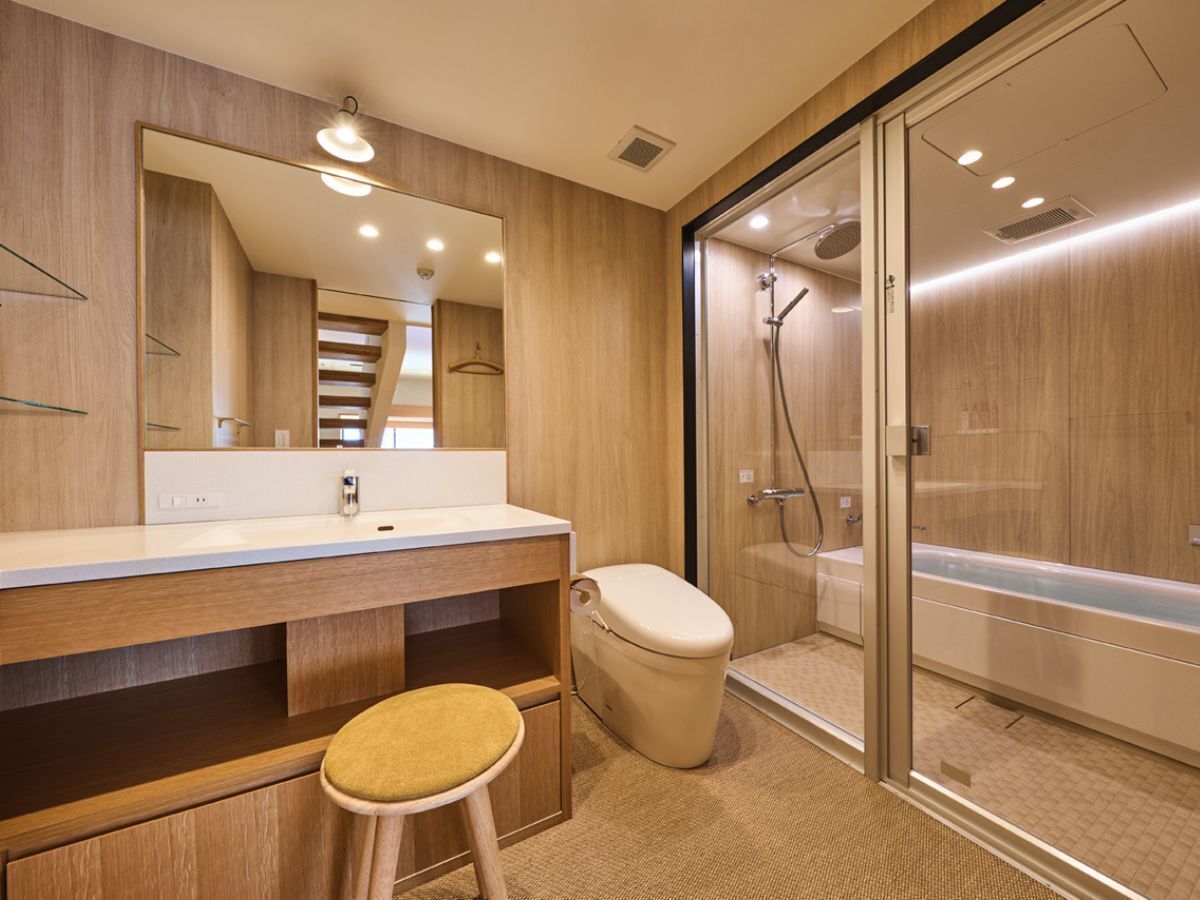 Un baño moderno con tocador de madera, inodoro, cabina de ducha de vidrio y un espejo grande.