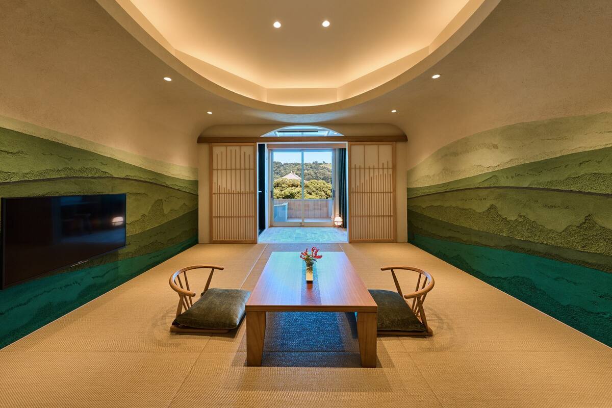 A spacious room with a long table, chairs, and a flat-screen TV mounted on the wall.