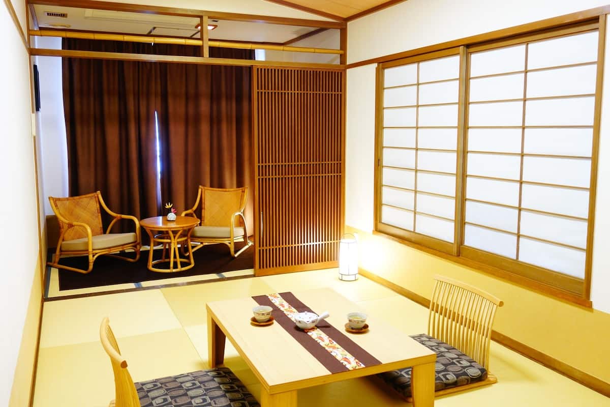 A traditional Japanese room with tatami flooring, a low table with cushions, and sliding doors.
