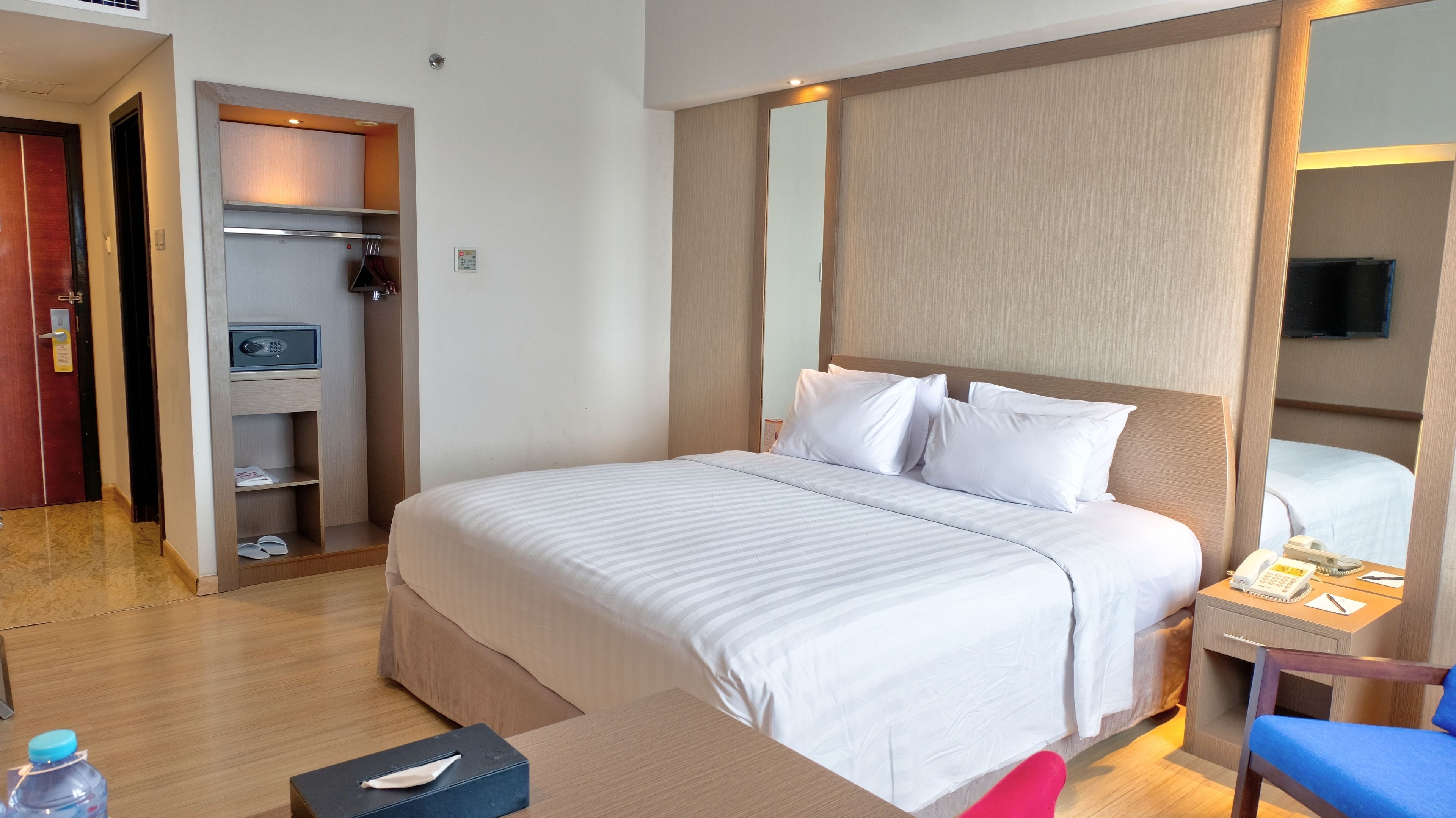 A hotel room with a bed, bedside table, and a wardrobe.