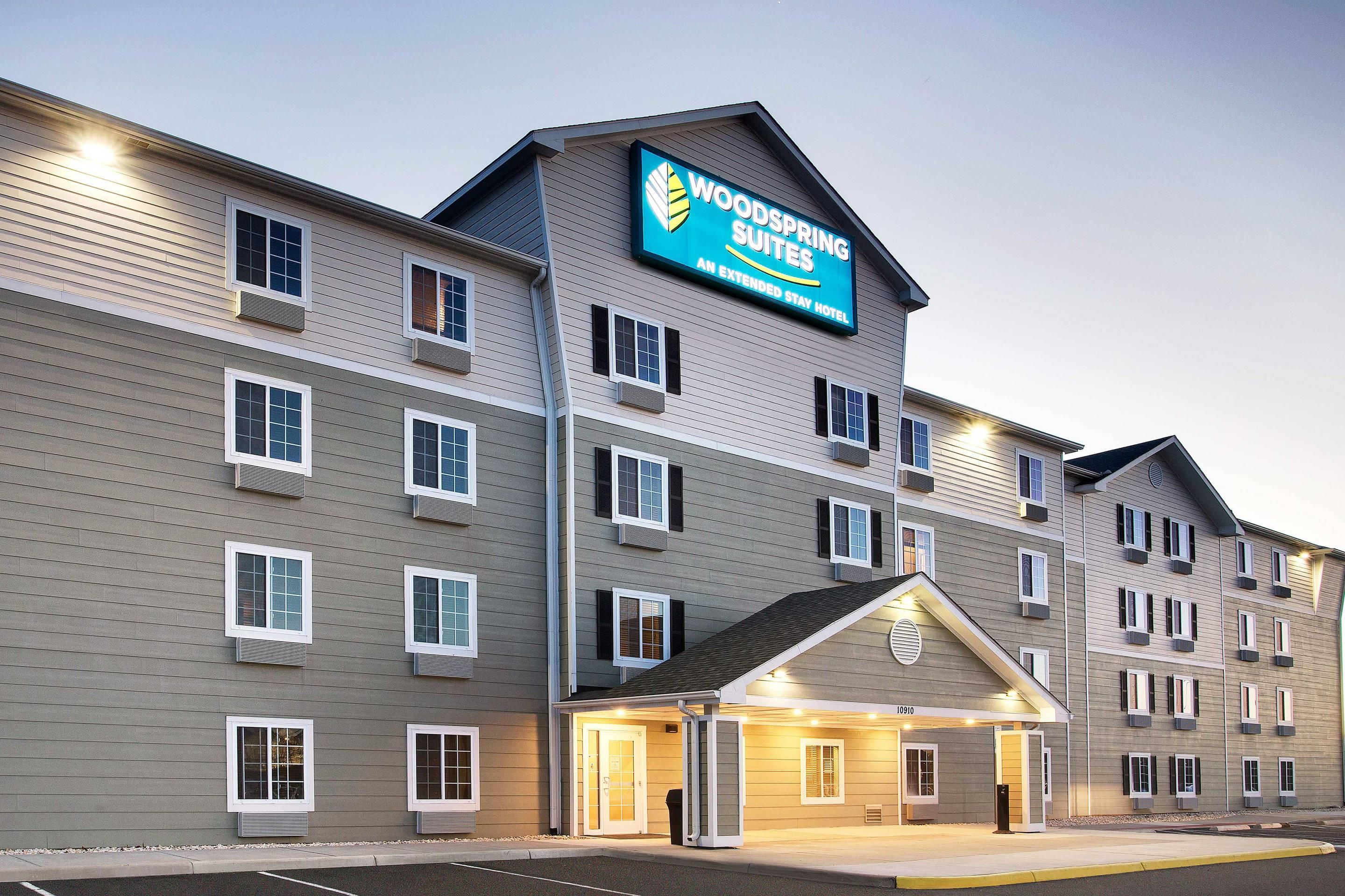 A multi-story hotel with a prominent sign for Woodspring Suites.