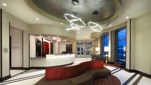 A hotel lobby with a reception desk, a curved seating area, and large windows offering a view of the cityscape. - Residence Inn Boston Needham (Needham)
