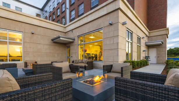 An outdoor seating area with wicker furniture and a central fire feature. - Residence Inn Boston Needham (Needham)