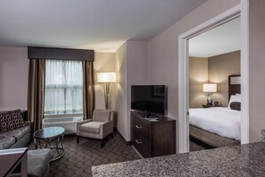 A hotel room with a bed, a TV, a desk, a chair, a lamp, and a window with curtains. - Residence Inn Boston Needham (Needham)