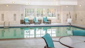 A pool area with lounge chairs and a table, large windows, and a tiled wall. - Residence Inn Largo Medical Center Drive (Upper Marlboro)