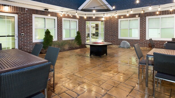 An outdoor patio area with brick walls, a fire pit, and outdoor seating. - Residence Inn Largo Medical Center Drive (Upper Marlboro)
