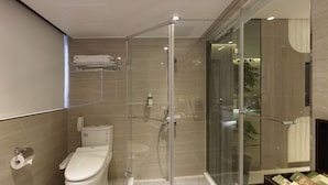 Een moderne badkamer met een douche met glazen wand, een toilet en een handdoekhouder.