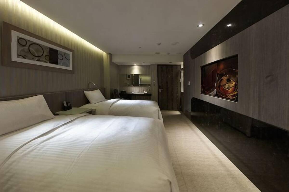Ein Hotelzimmer mit zwei Betten, einem großen Spiegel und einem Fernseher.