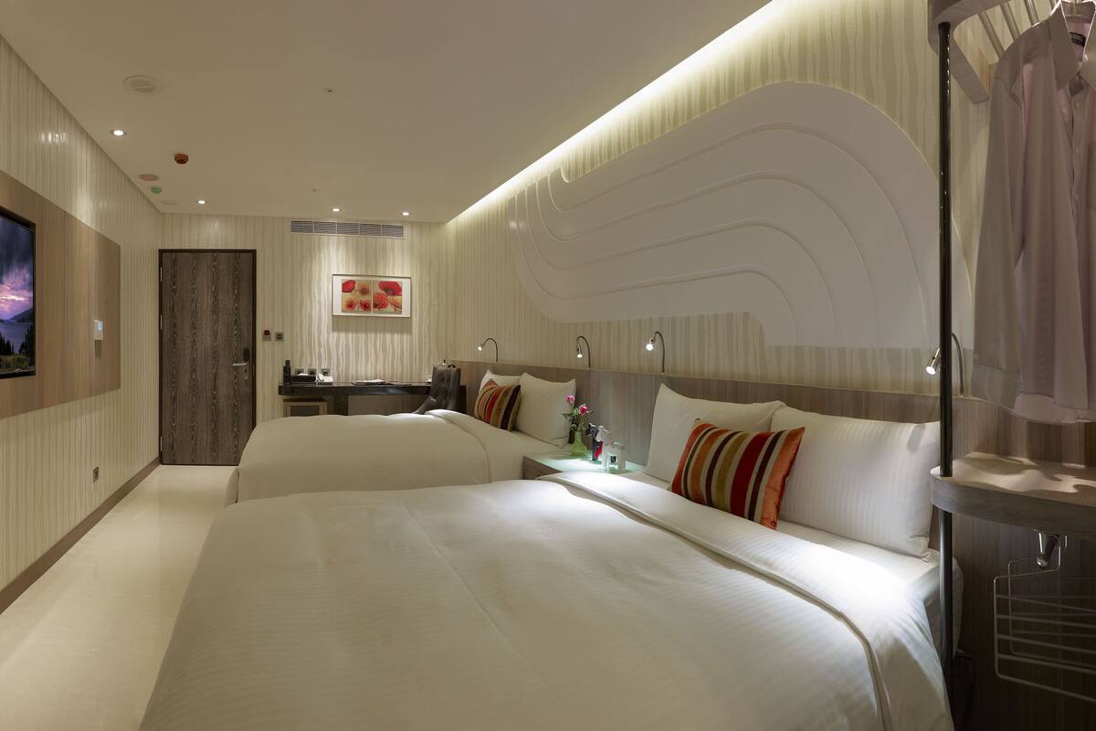 Ein modernes Hotelzimmer mit einem großen Bett, einem Schreibtisch und einem Fernseher, der eine schöne Landschaft zeigt.
