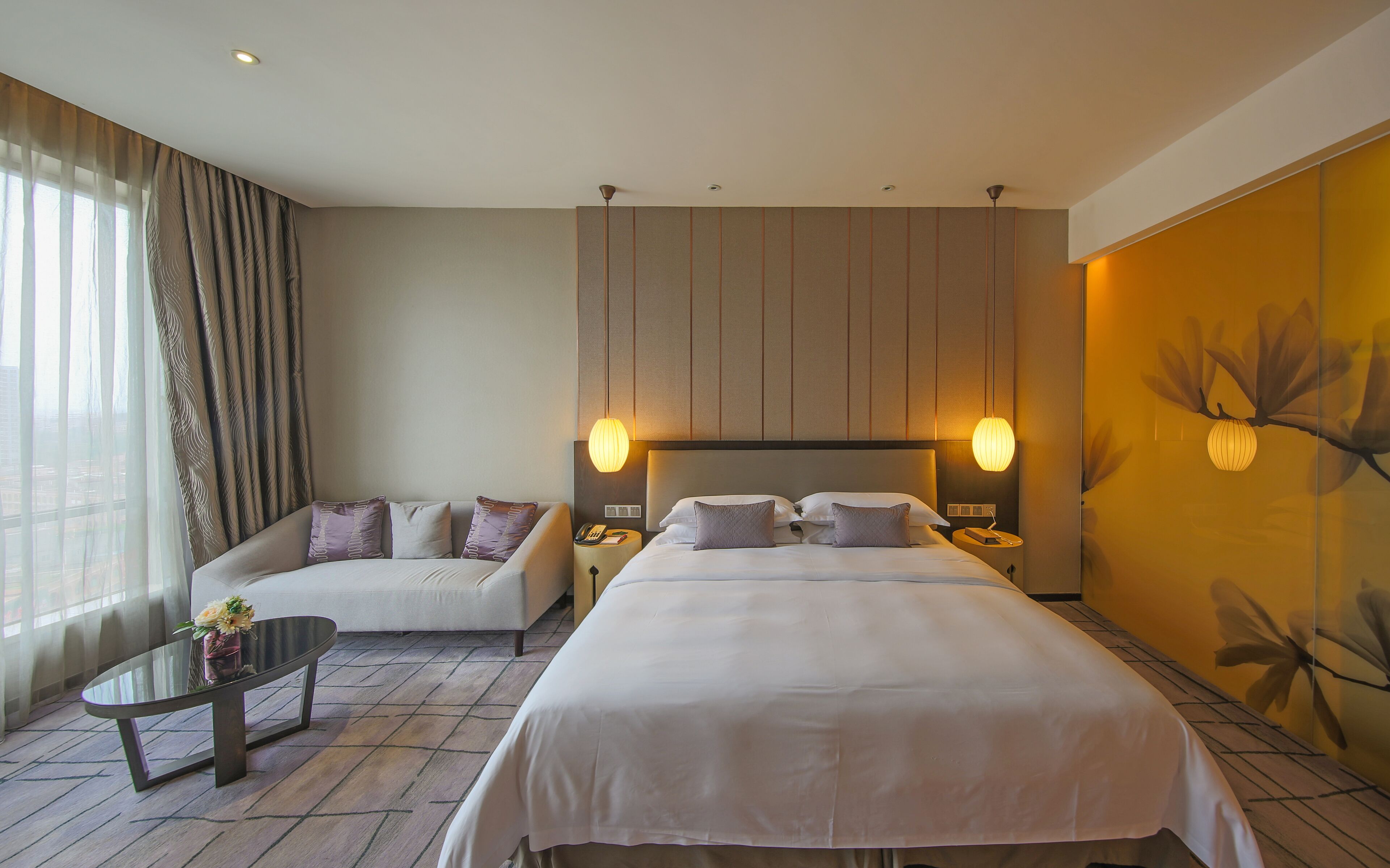 A hotel room with a bed, a sofa, a small table, and a nightstand.