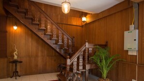 A wooden staircase with a decorative railing, a potted plant, and a statue of an elephant. - Baan Khun Nang Colonial Residence (Koh Samui)